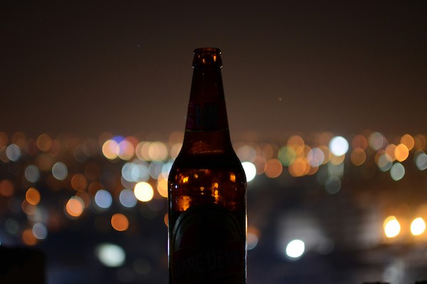 bottle of beer in the dark in front of background lights