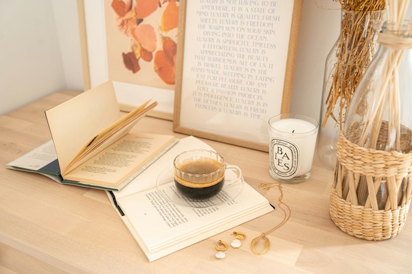 cup of coffee with book, candle, and natural diffuser on a desk