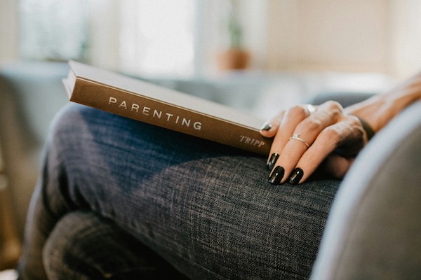 woman seated with parenting book on her lap