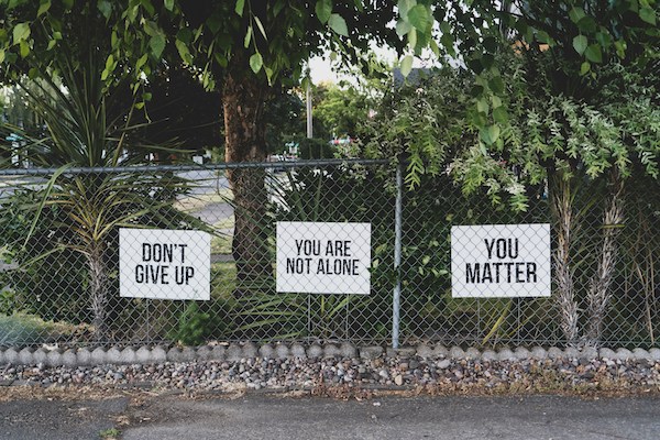 signs on a fence that read "Don't give up," "You are not alone," and "You matter"