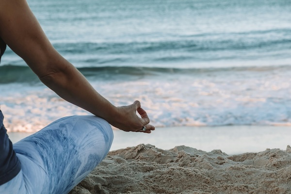 woman sitting in a mindfulness pose on the beach