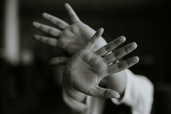 black and white hands crossed and pushing away in fear